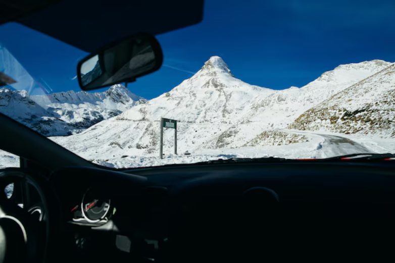 Photo de l'interieur d'une voiture avec en arriere plan la montagne remplie de neige taxi